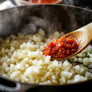 Dutch oven on a stovetop, showing diced onions being sautéed