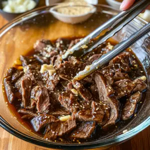 Large glass mixing bowl filled with thinly sliced beef