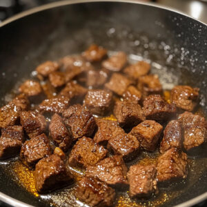 beef cubes are being seared in small batches