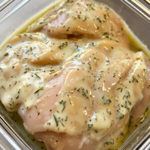 raw chicken thigh coated in a yogurt marinade