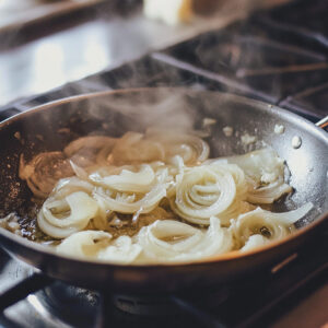 skillet on a stovetop, filled with sliced onions