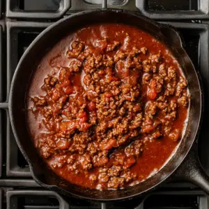 browned ground beef simmering in a rich, deep red sauce