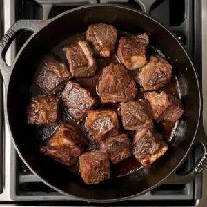 large chunks of beef chuck roast searing to a deep golden brown
