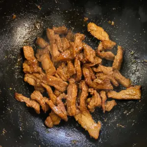 sliced pork strips sizzling in hot oil