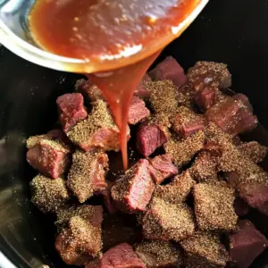 slow cooker filled with uncooked, seasoned, large beef chunks