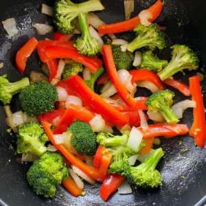thinly sliced onions, and bright green broccoli florets being sautéed
