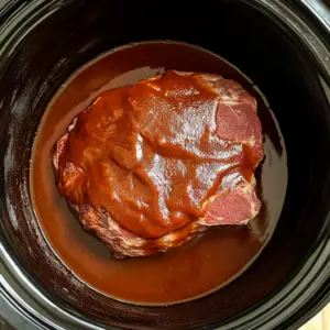 uncooked chuck roast sitting in the center of a slow cooker