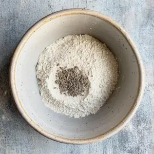 all-purpose flour with visible specks of carom seeds and cumin seeds