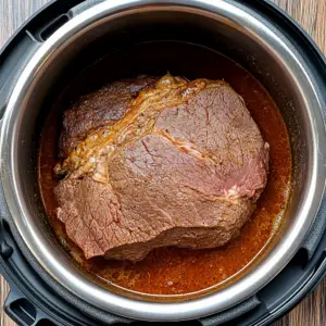 beef chuck roast sizzling in the bottom of an Instant Pot