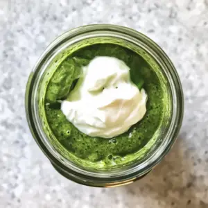 blender jar containing a smooth, vibrant green mixture of blended mint, cilantro, chili, and water