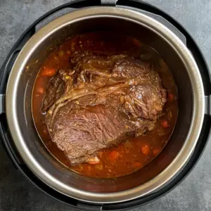 seared beef chuck roast sitting in the stainless steel inner pot