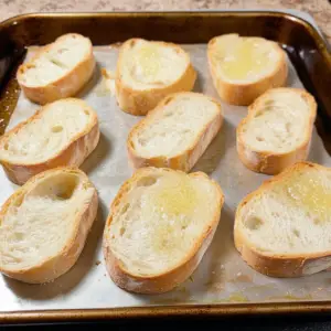 several baguette slices neatly arranged on a baking sheet