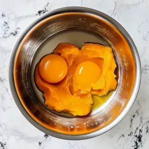 vibrant orange pumpkin puree sits alongside two glossy egg yolks