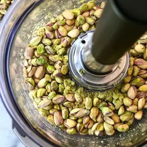 food processor bowl filled with raw, unsalted pistachios