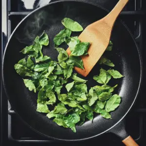 fresh green curry leaves being dry roasted