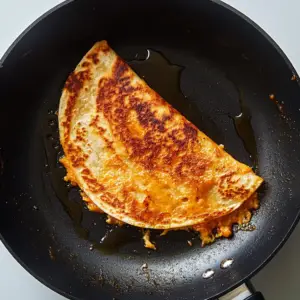 golden-brown quesadilla cooking in a nonstick skillet