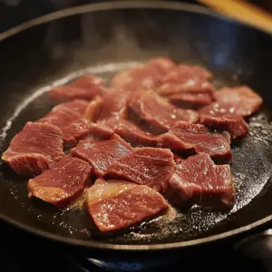 sliced strips of beef searing in a hot skillet