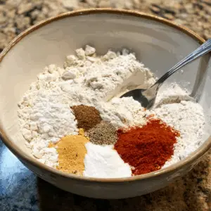 large mixing bowl on a kitchen counter filled with dry ingredients